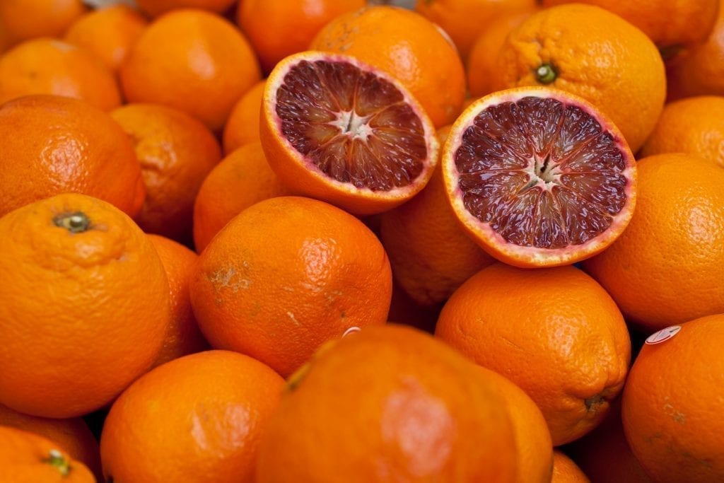 Stack of blood oranges with one in half cut on top. Oranges are a popular Sicily food
