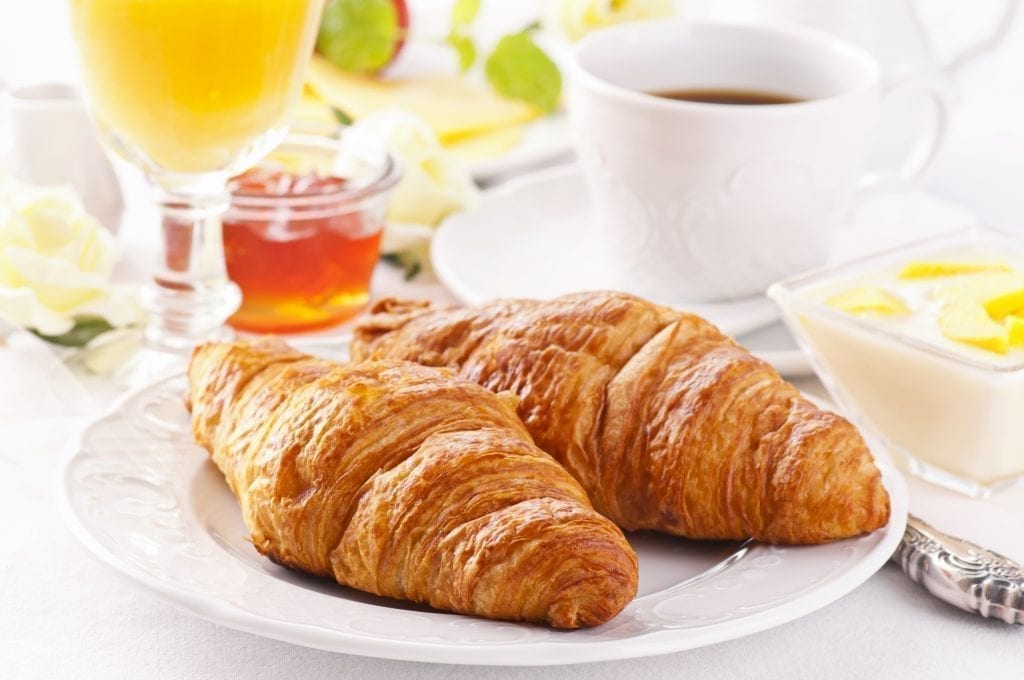 Typical breakfast in France of croissants with coffee and juice, along with jam and butter
