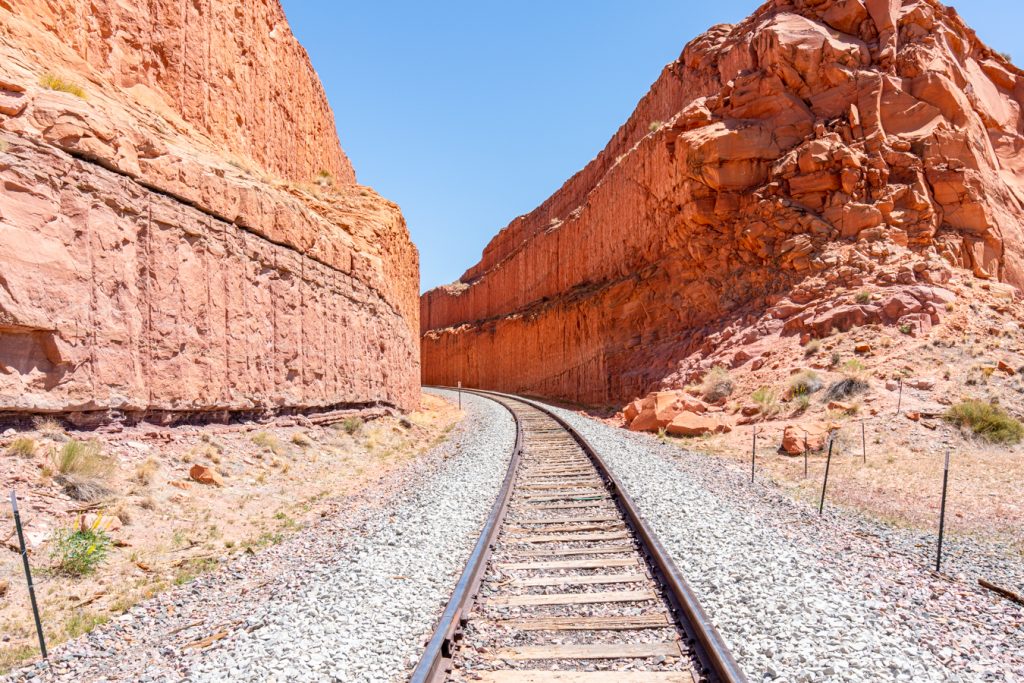 railroad tracks leading into a sandstone tunnel in utah