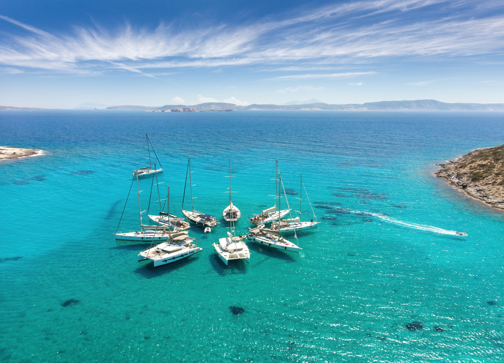 collection of sailboats gathered together in the waters of greece