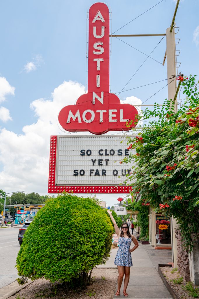 kate storm standing undernath the iconic austin motel sign on south congress