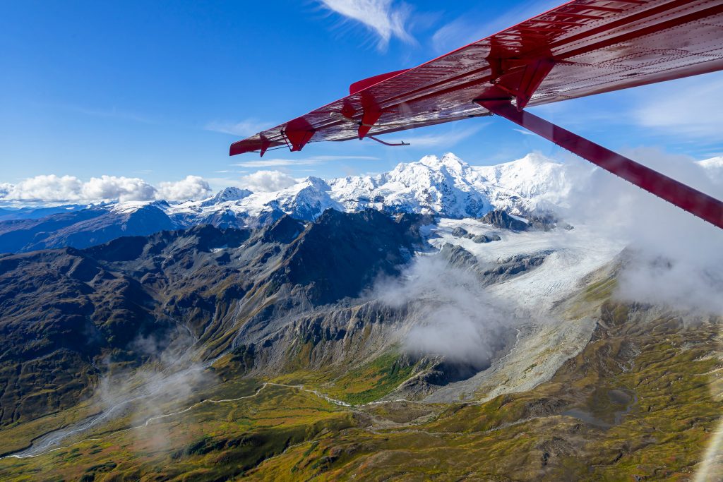 view of snowcapped mountains in alaska from a small red plane on a flightseeing tour, one of the top things to do in usa