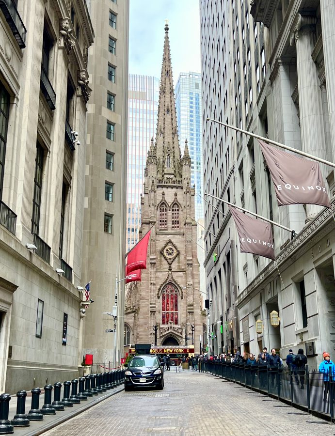 front facade of trinity church as seen from wall street with cobblestones in the foreground, financial district new york city