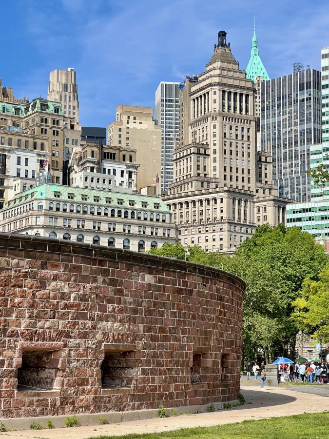 view of skyscrapers in fidi new york city with a piece of brick castle clinton in the foreground
