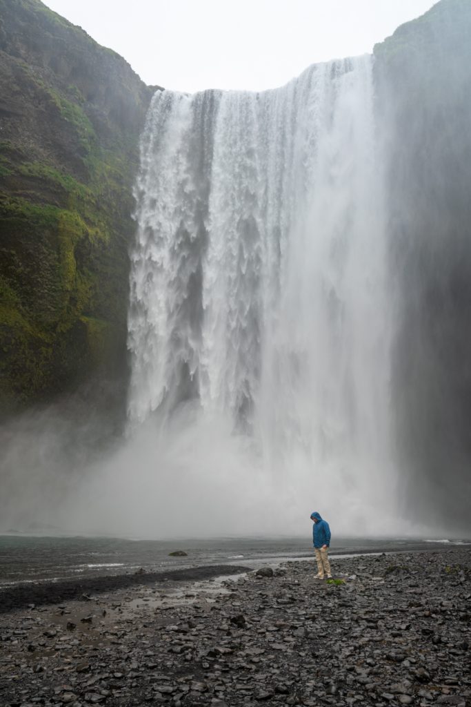 jeremy storm in front of skogafoss waterfall wearing blue jacket