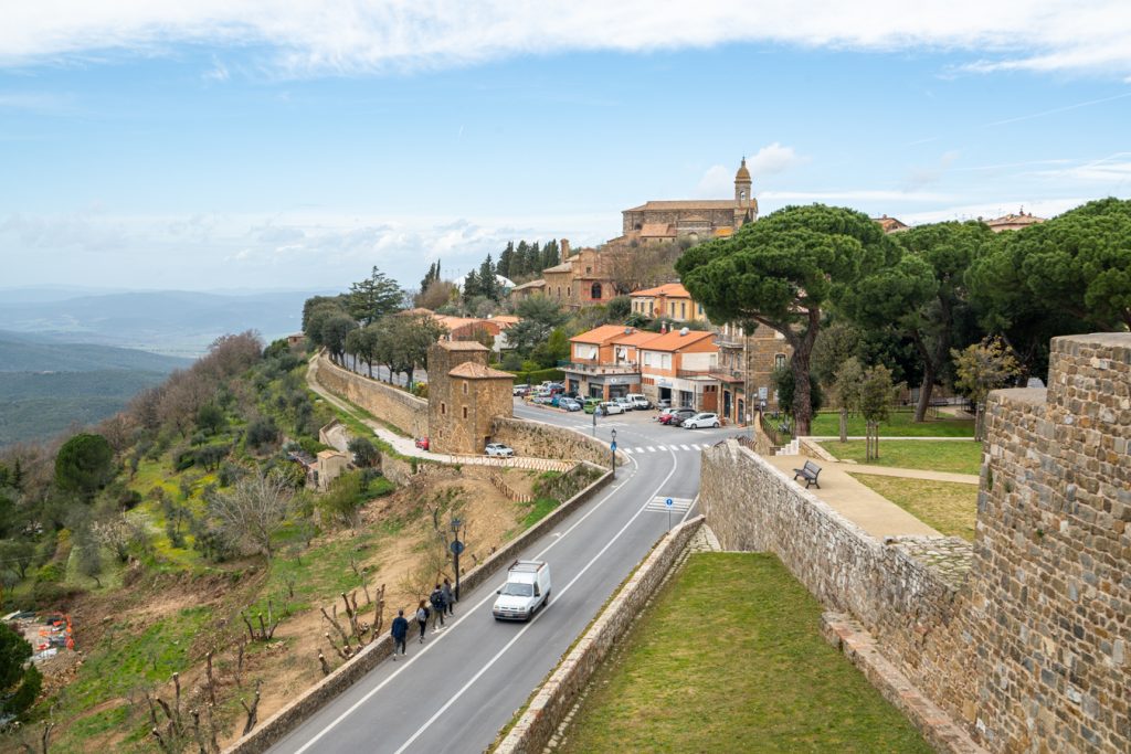 view of montalcino tuscany with a couple cars driving down a road in the foreground