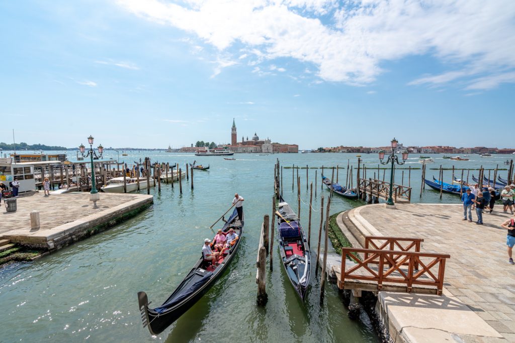 view of gondolas with san giorgio maggiore in the background on a sunny day in venice italy