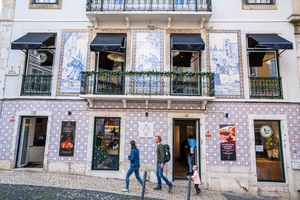 people in jackets walking by santo antonio bakery in lisbon winter