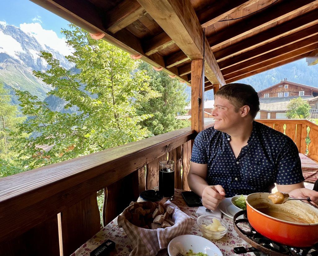 jeremy storm eating fondue at mountain hostel gimmelwald overlooking the alps