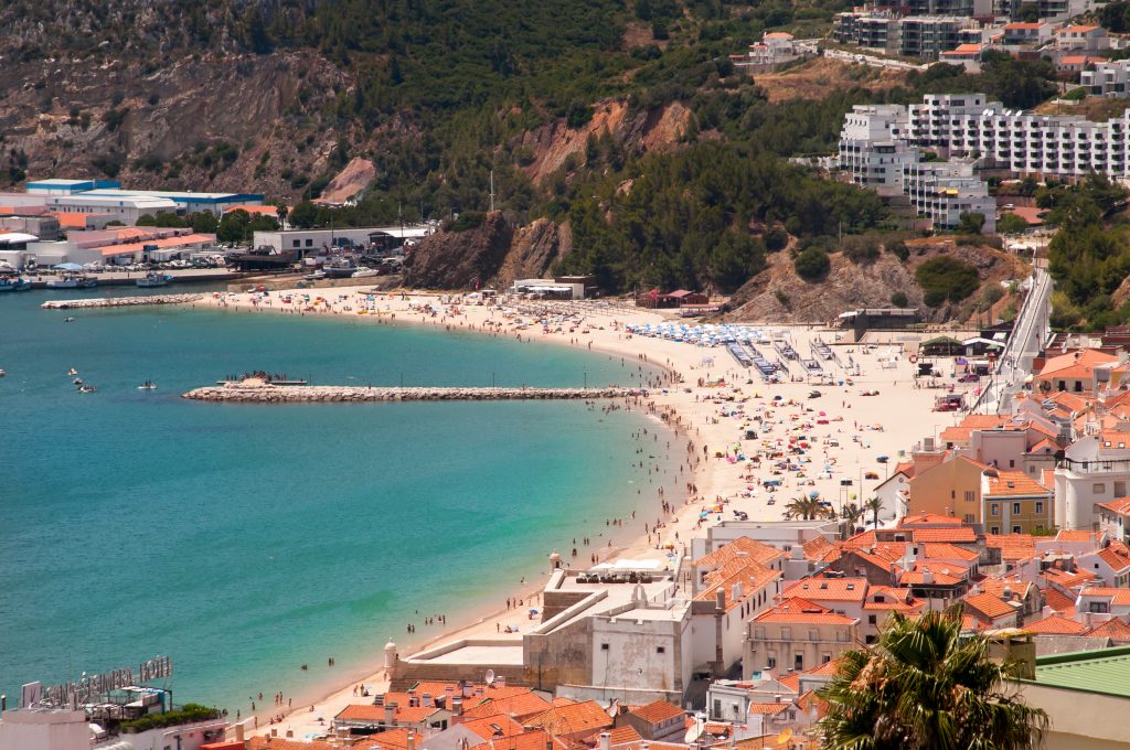 sesimbra portugal beach town as seen from above, with ocean to the left. sesimbra is one of the best coastal towns in portugal to visit