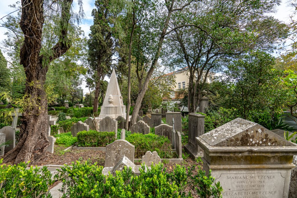 gravestones under shade trees in the british cemetery of lisbon estrela