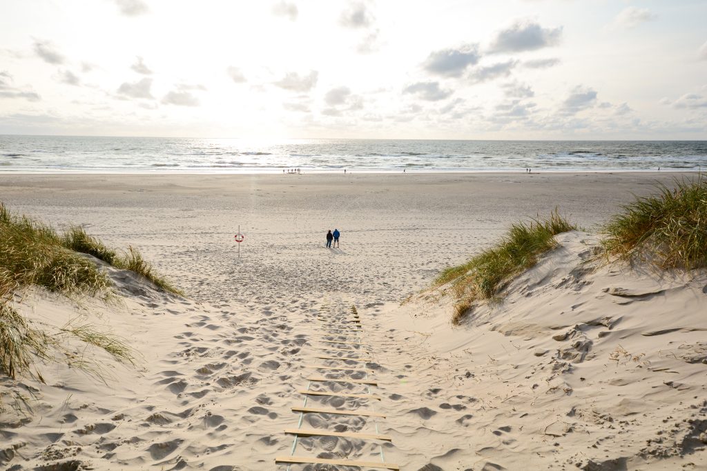 two people in the distance on a sandy beach at sunset near copenhagen, one of the best beach cities in europe