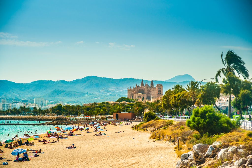 beach in palma spain with sand in the foreground and cathedral in the background