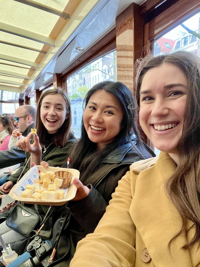 kate storm christina guan and sophie nadeau holding up cheese and wine on an amsterdam canal cruise