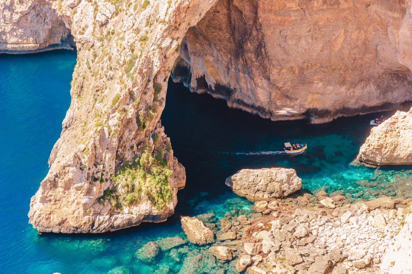 view of blue grotto malta from above with boat visible in the distance