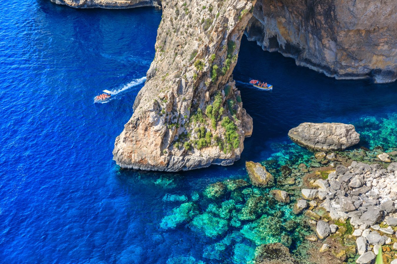 two boats passing through blue grotto in malta as seen from above