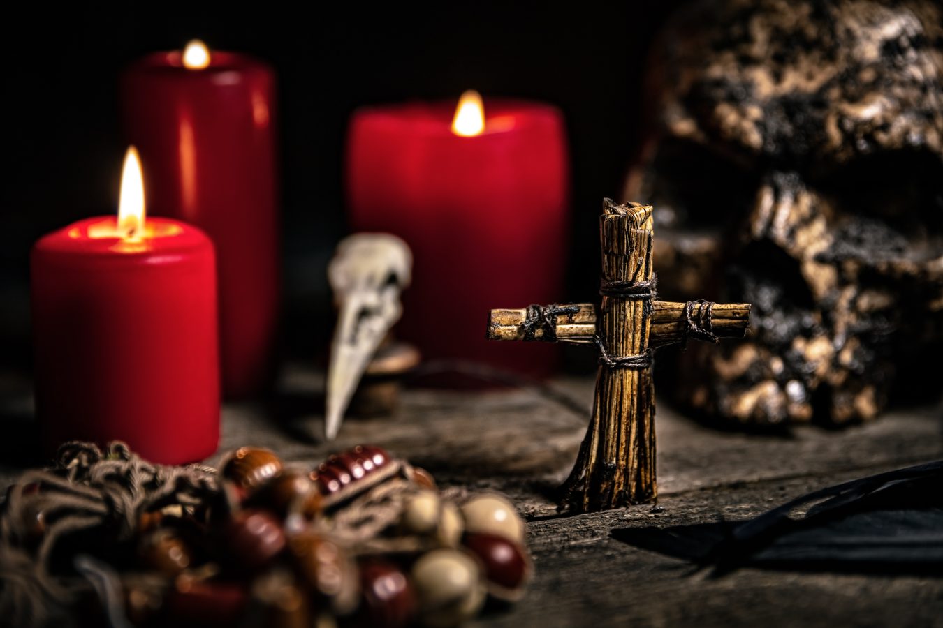 collection of voodoo items laid out on a table with red candles
