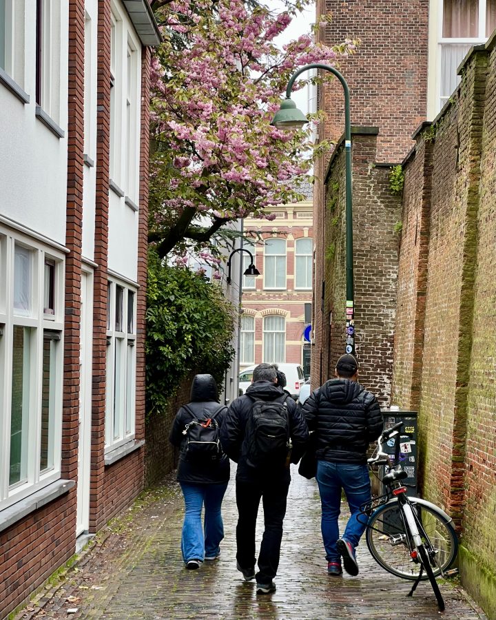 people walking through a small street on a rainy day in delft