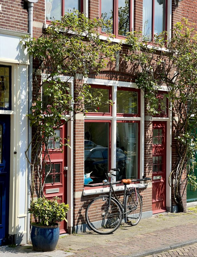 view of a bike parked outside a small shop as seen in the historic center of a delft, a fun place to explore on a day trip to delft from amsterdam