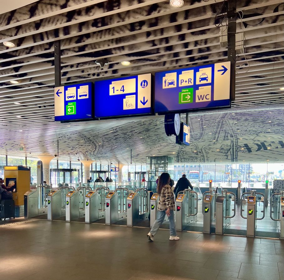 interior of delft train station with directional signs hanging from the ceiling