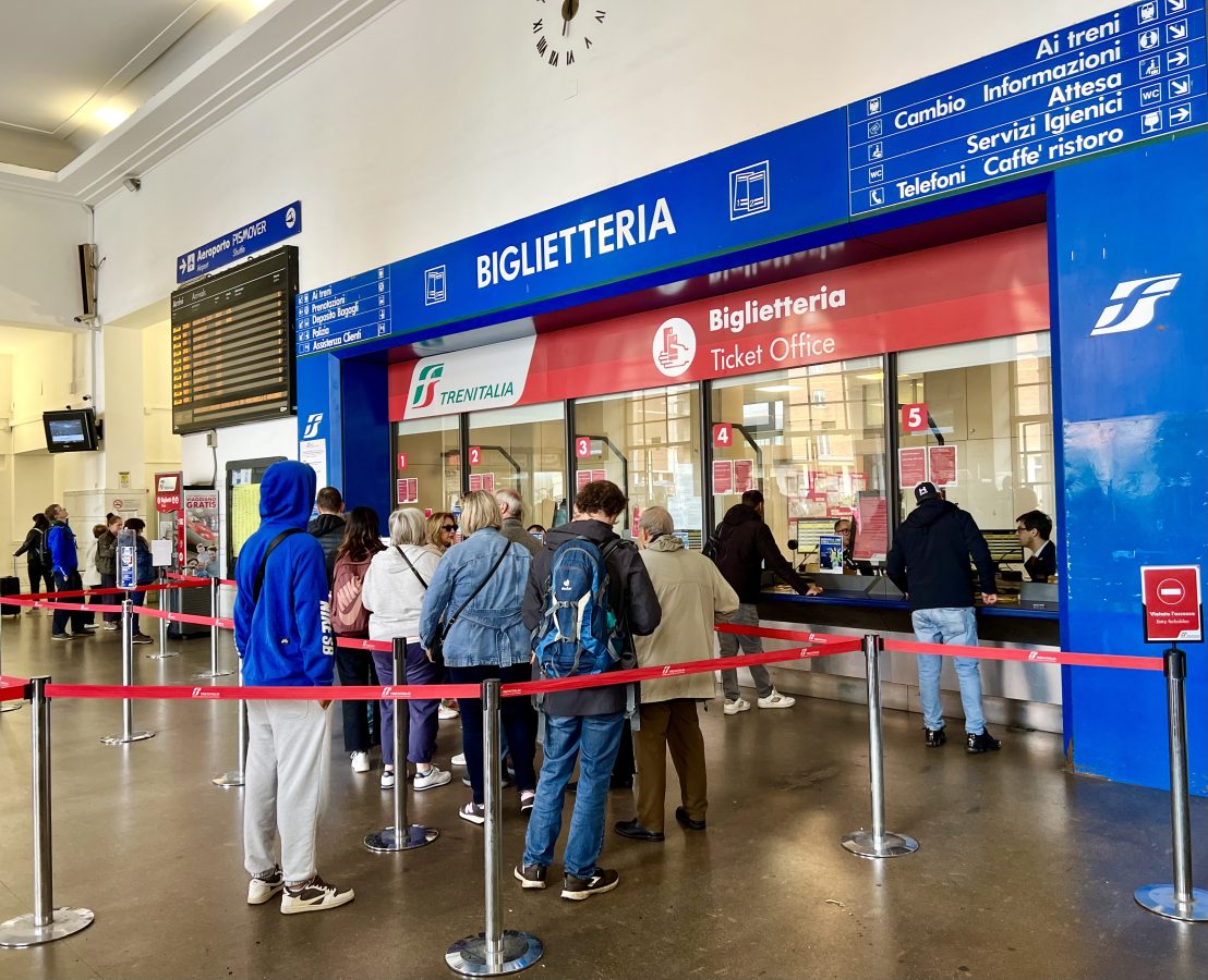 travelers lining up to purchase train tickets at pisa centrale as seen during a pisa day trip from florence