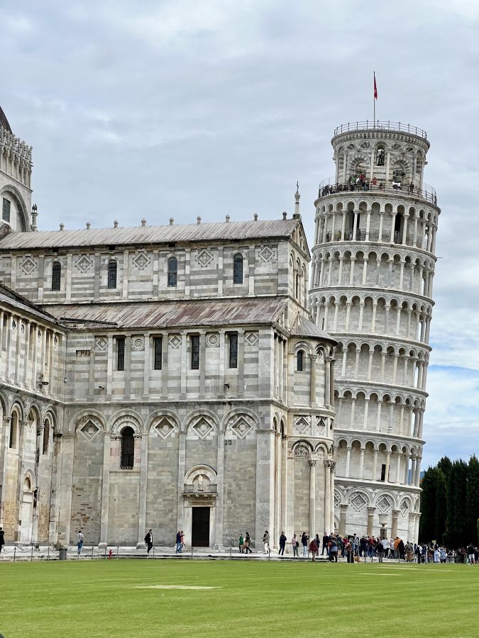 view of the leaning tower of pisa across the piazza dei miracoli with part of the duomo in front of it