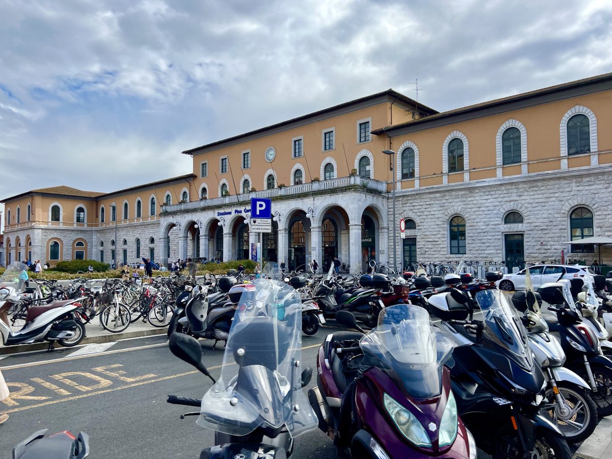 front facade of pisa centrale train station with motorbikes parked in front of it