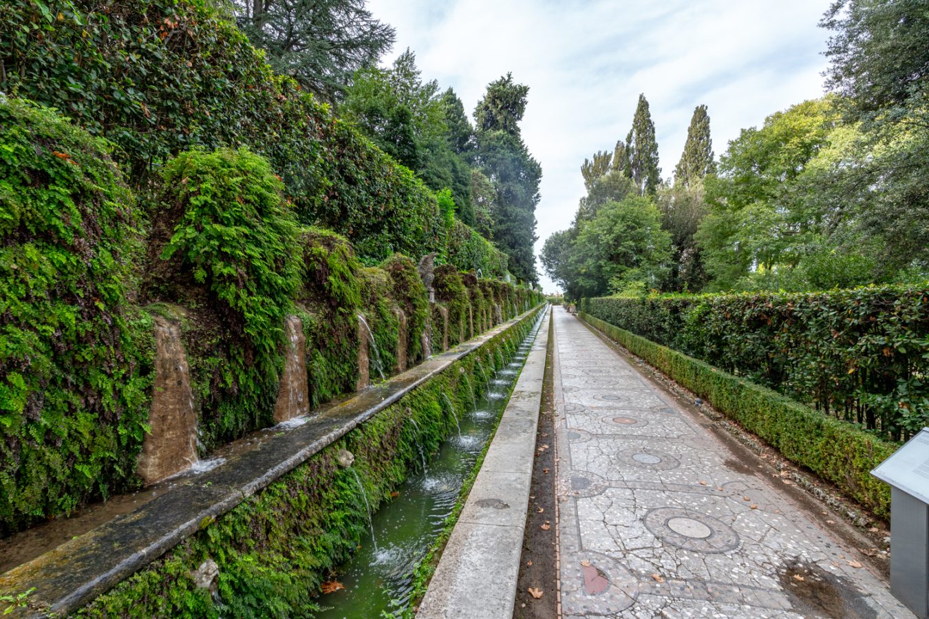 many small waterfalls lining a pathway in the gardens of villa d'este, one of the best things to do in tivoli italy