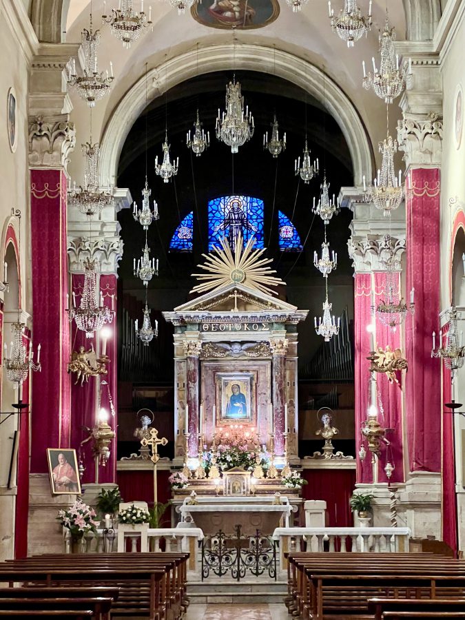interior of the church of santa maria maggiore in tivoli, with chandeliers hanging over the altar and red decorating the aisles
