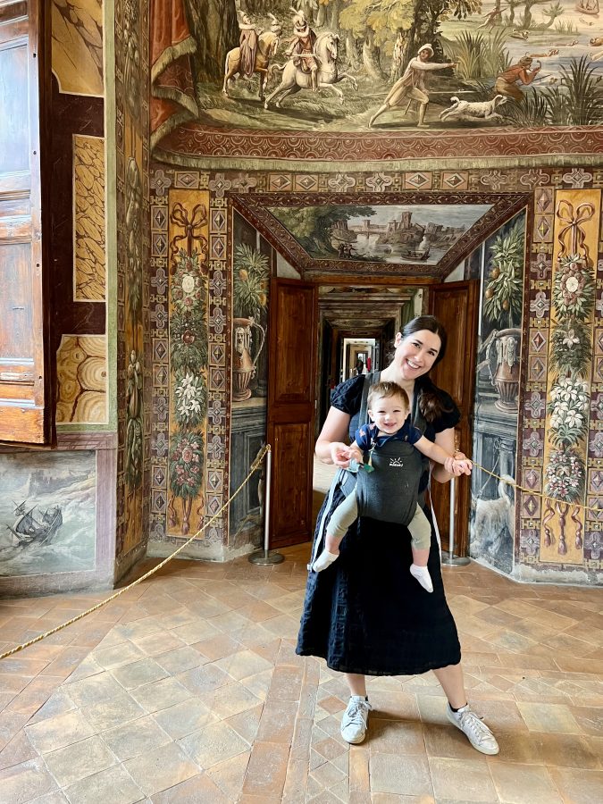 kate storm and her baby inside villa d'este with frescoes behind them, one of the top things to see when spending one day in tivoli itinerary