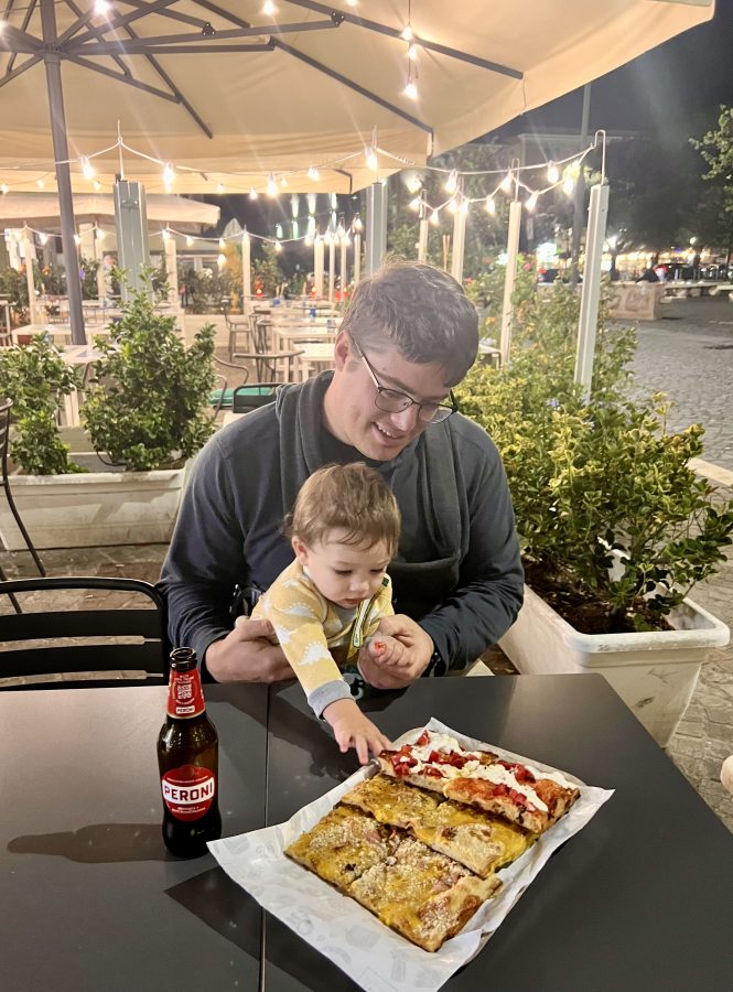 jeremy storm and his baby enjoying a plate of pizza by the slice in tivoli at night